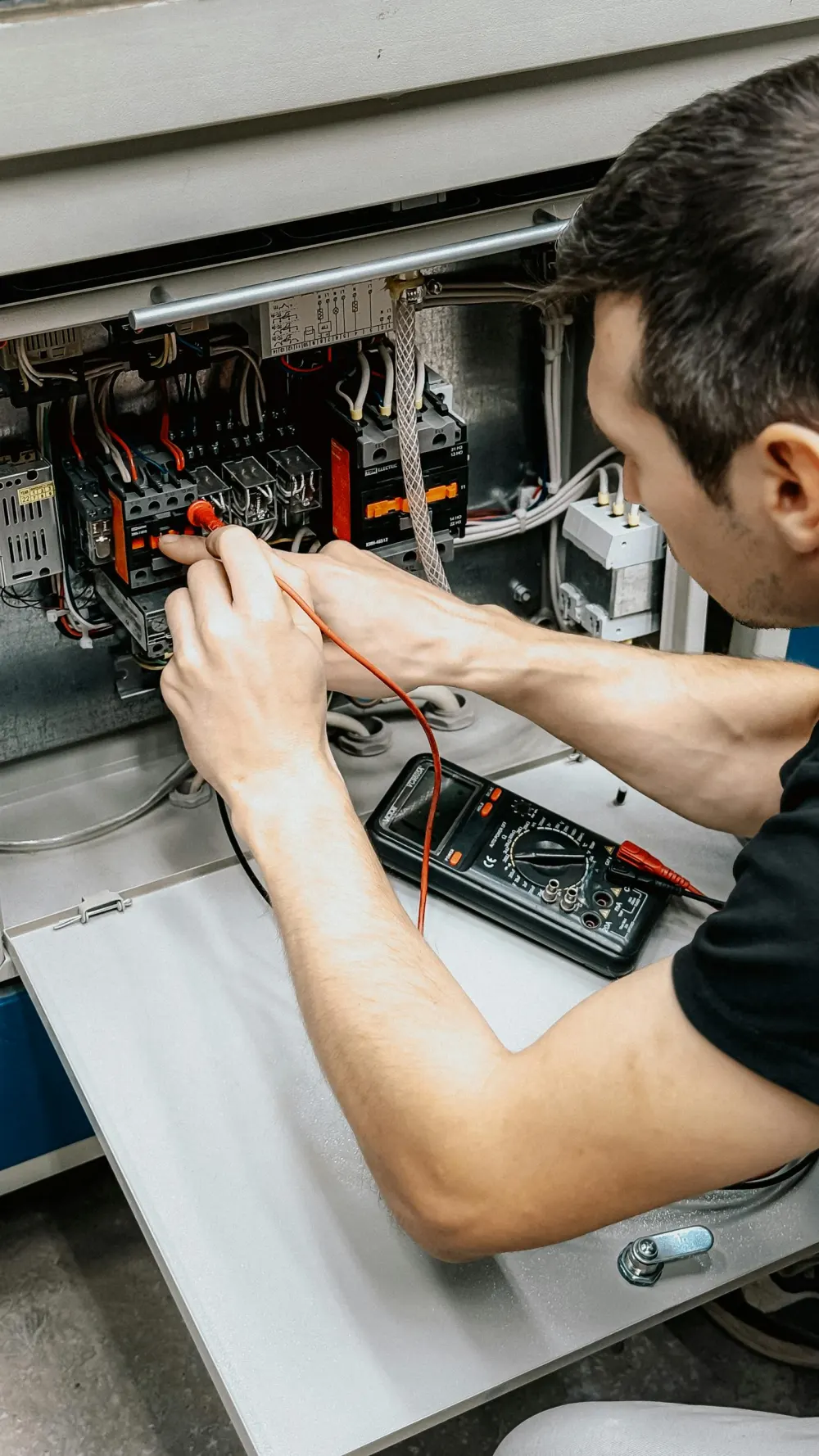 Electricista profesional comprobando cuadro eléctrico con multímetro